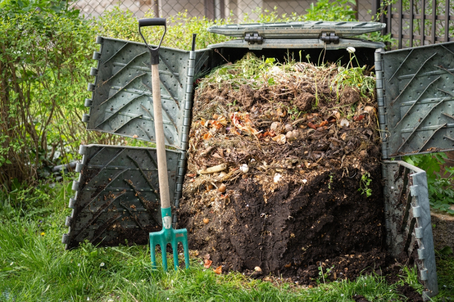 black plastic compost bin with side doors - full of decomposing compost showing the most composted layers at the bottom and fresh at the top