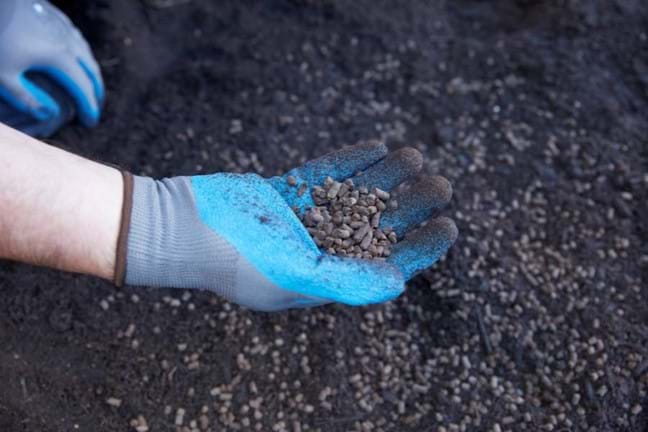 Gloved hand with Yates Dynamic Lifter fertiliser pellets