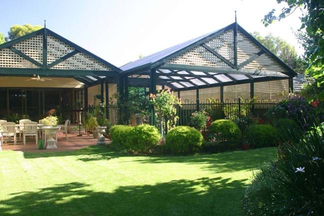 A suburban backyard with two pergolas and a lush green lawn