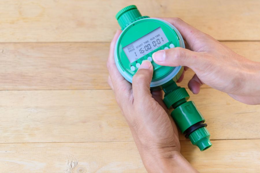 A pair of hands configuring a tap timer for irrigation