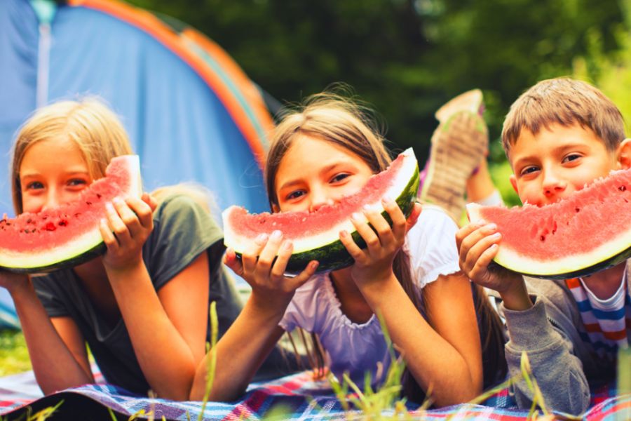 Three children enjoying fresh cut watermelon