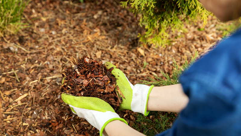 person wearing gloves and handling and applying fine bark mulch