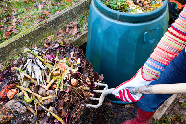 person using a fork to turn over fresh compost to add air and mix ingredients together
